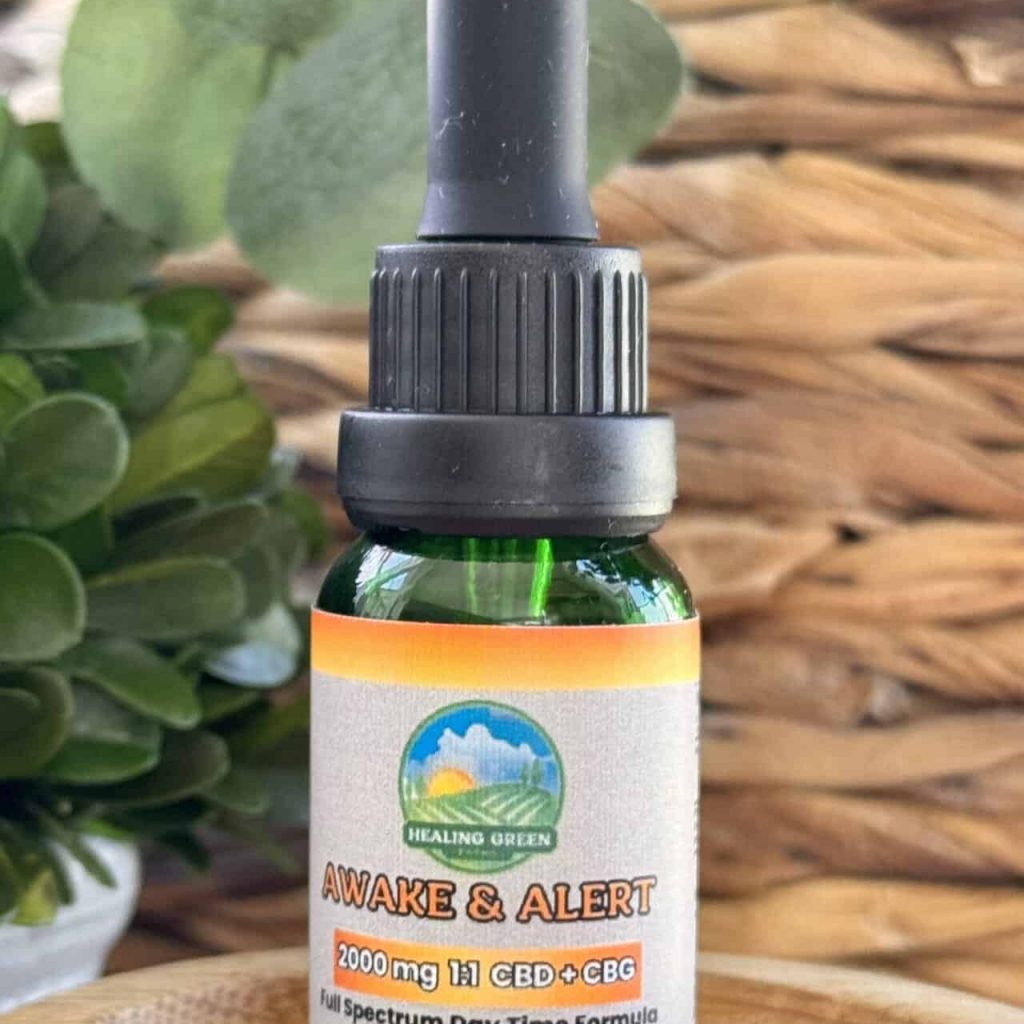 A 2000mg Full Spectrum Awake & Alert CBD + CBG dropper bottle sits on a woven surface, with green plants and a wicker basket in the background.